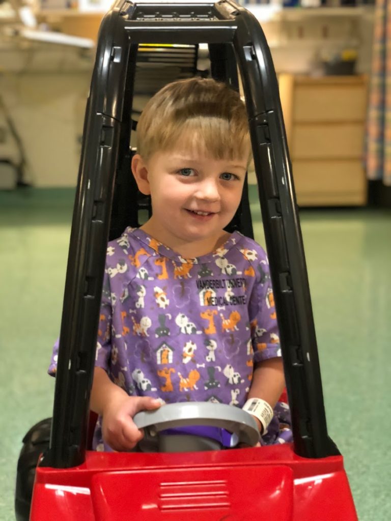 Toddler boy playing in a toy car before heart surgery.