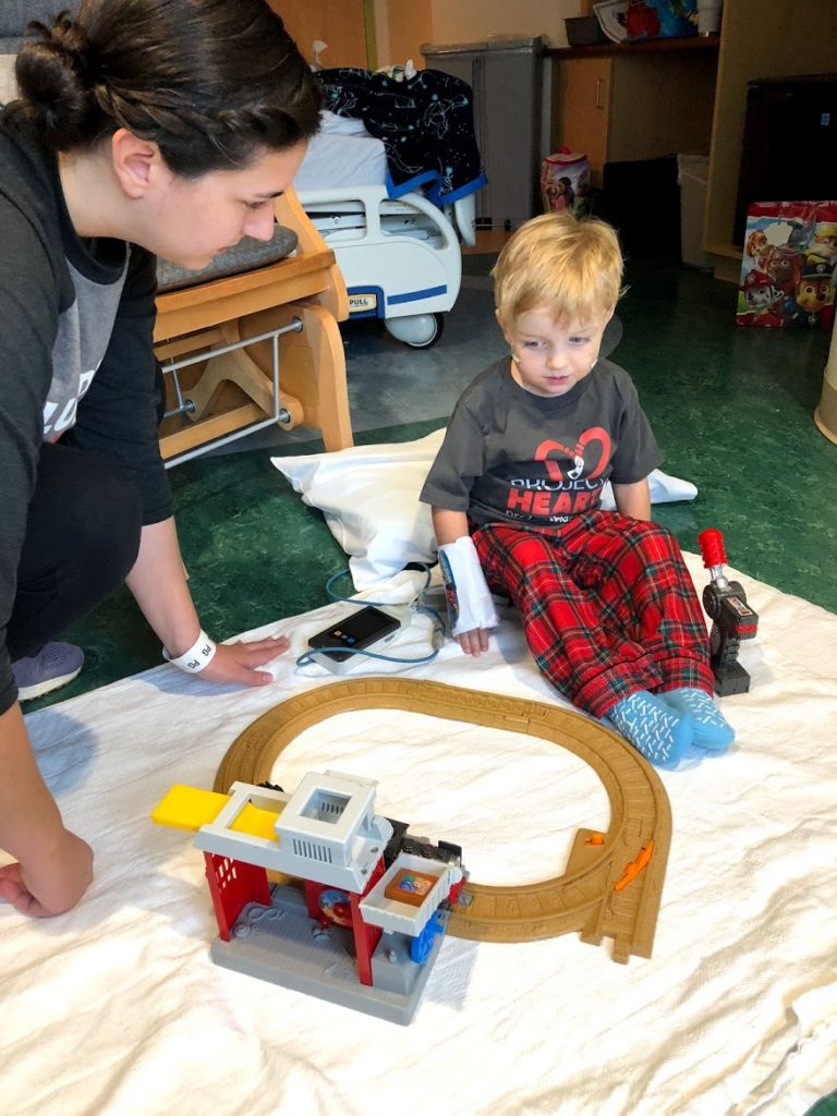 Little boy playing with toy train in the hospital.