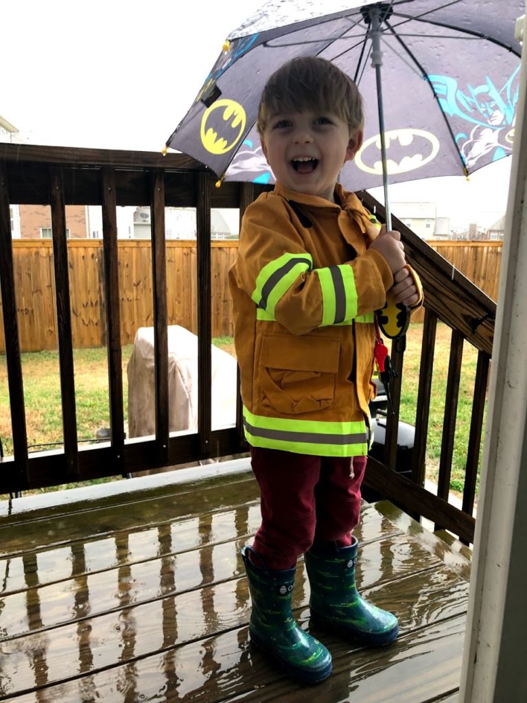 Boy using his new rain boots and umbrella gifts on a rainy day.